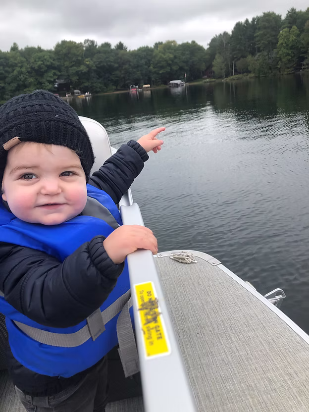 Toddler on boat pointing at lake.