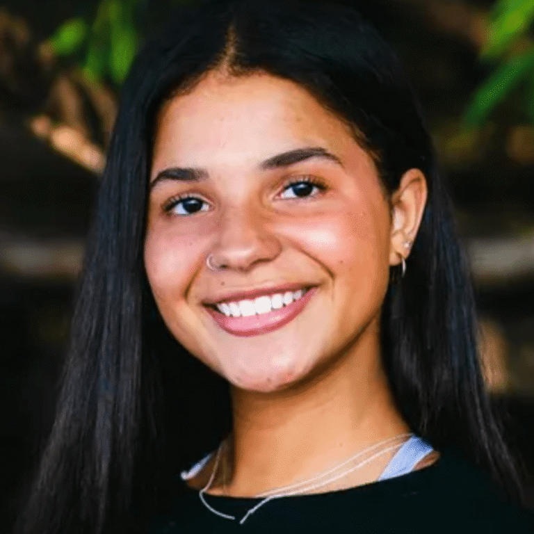 Smiling person with long dark hair.