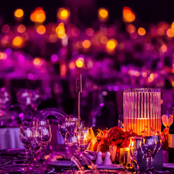 Elegant table setting with vibrant purple lighting and floral centerpiece.