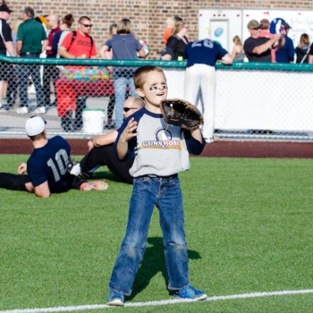 Young girl playing baseball on a sunny day at the field.